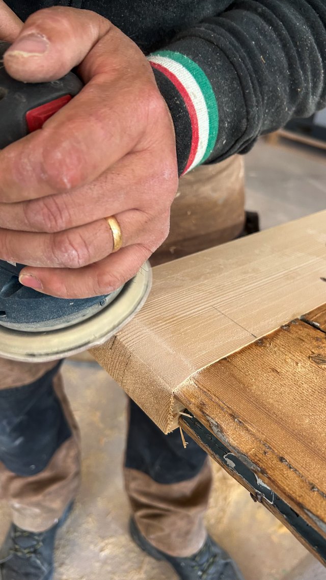 Mani al lavoro con levigatrice su un bordo in legno