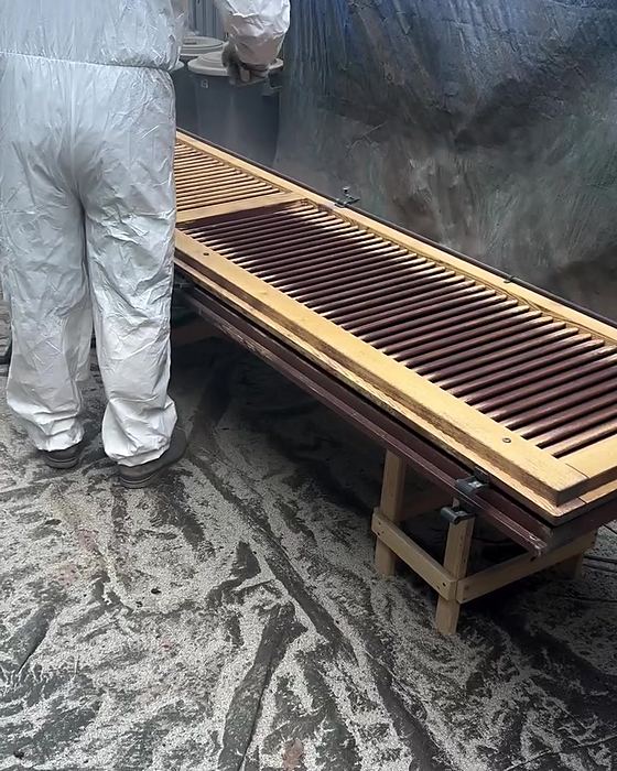 Operatore in tuta protettiva durante la verniciatura delle persiane