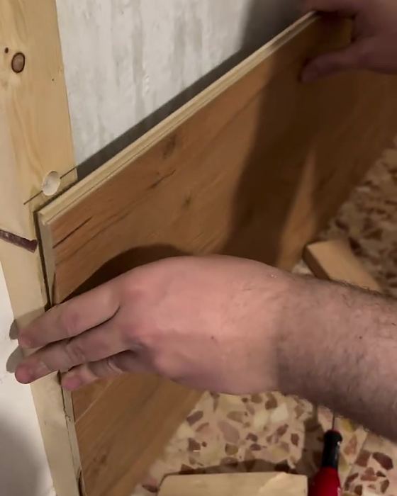 Mani che installano un pannello in legno sulla parete